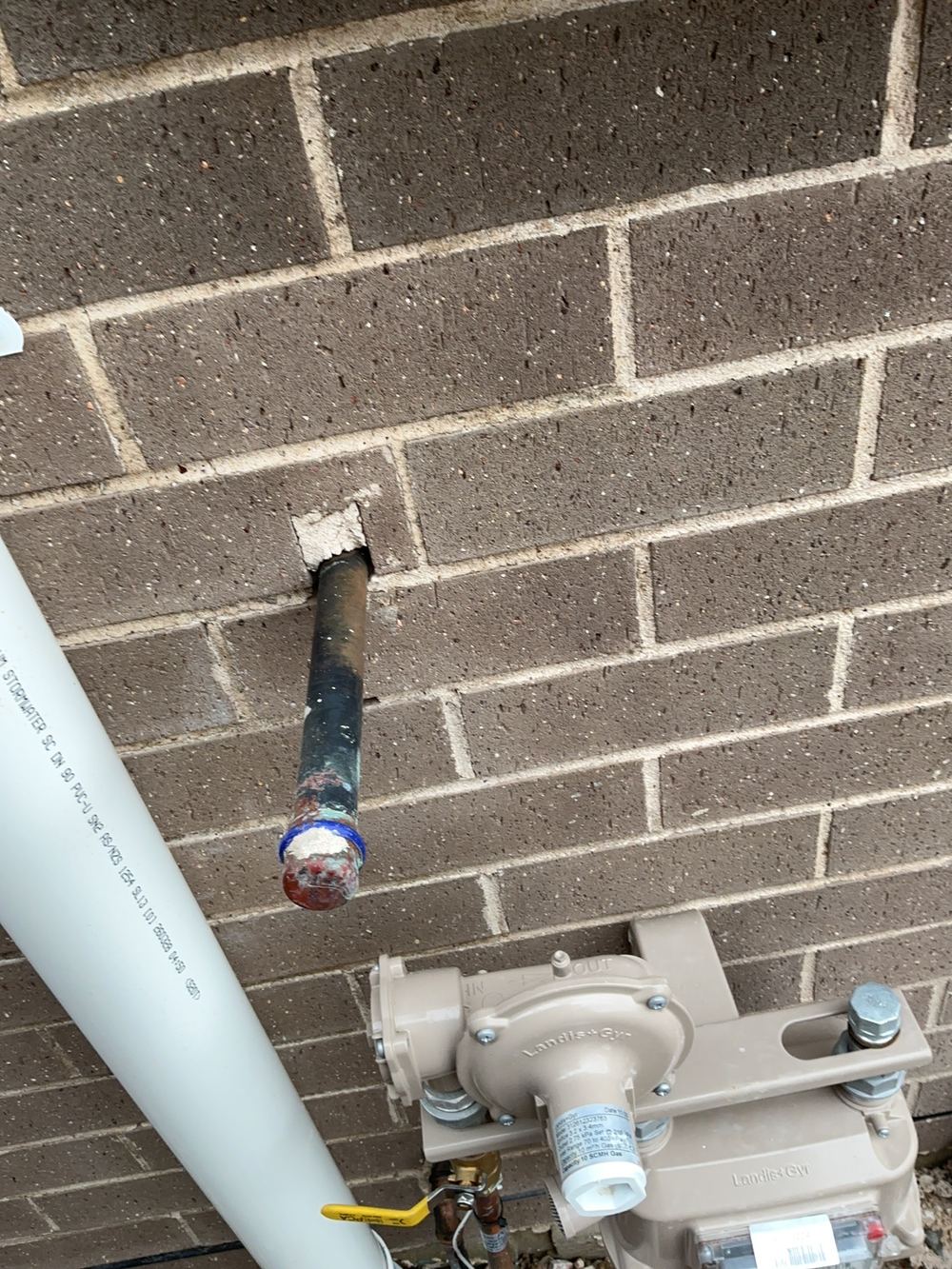 Service penetrations through the brick wall left unsealed around the pipe, found during a fixing inspection in Gables