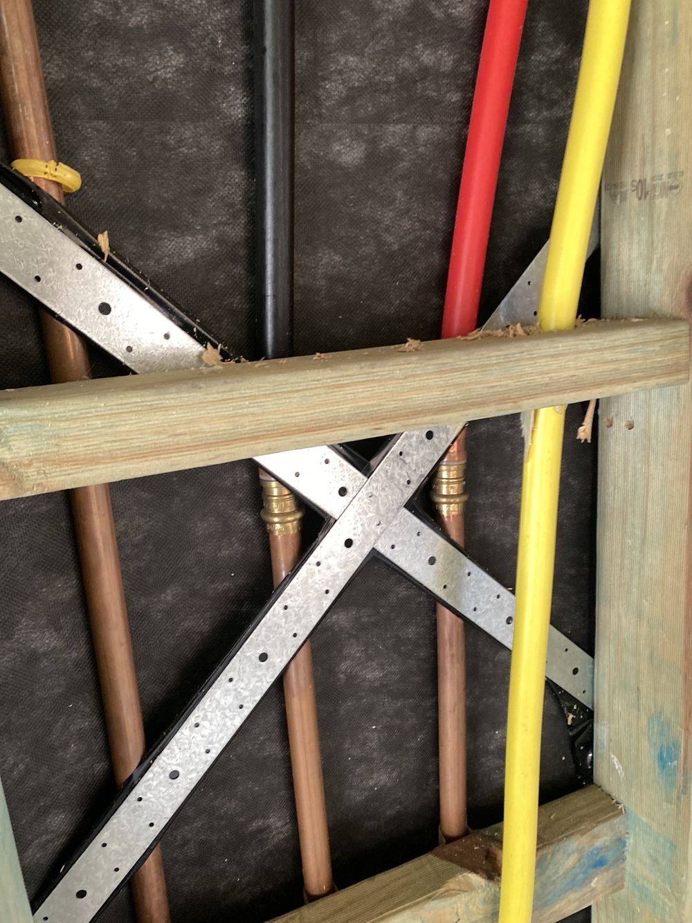 Water pipes resting on metal framing without a divider between them, found during a lock-up inspection in Gables